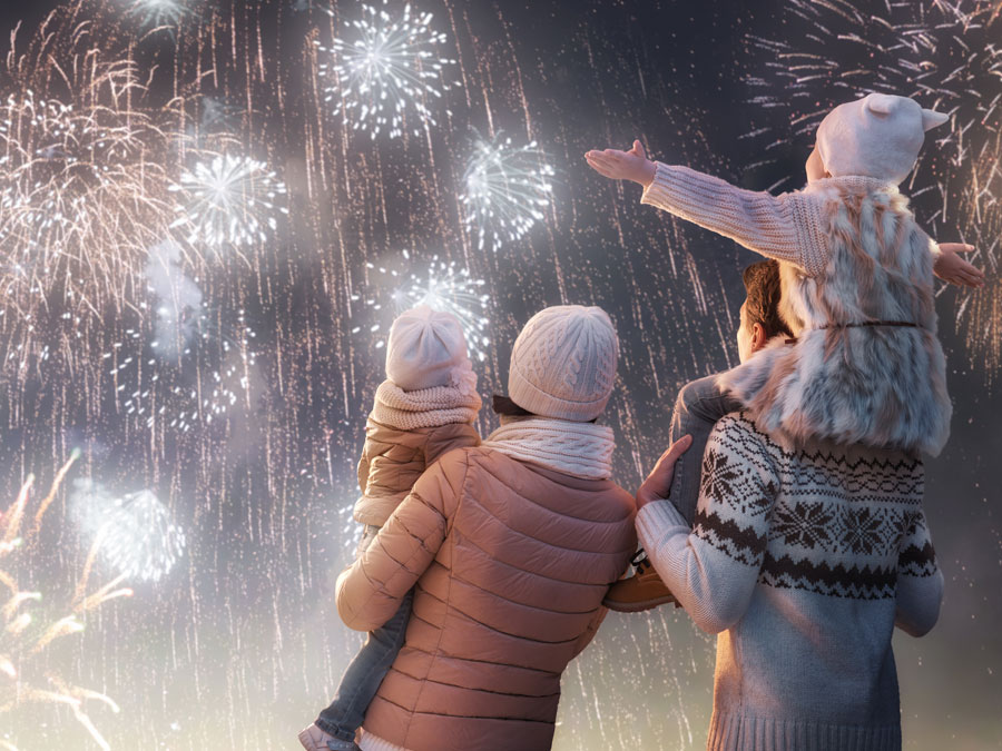 Kinder schauen mit ihren Eltern Feuerwerk im Winter